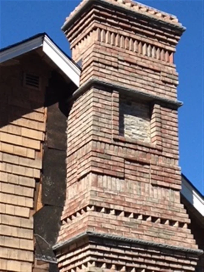 Detailed brick chimney on a house with wood siding